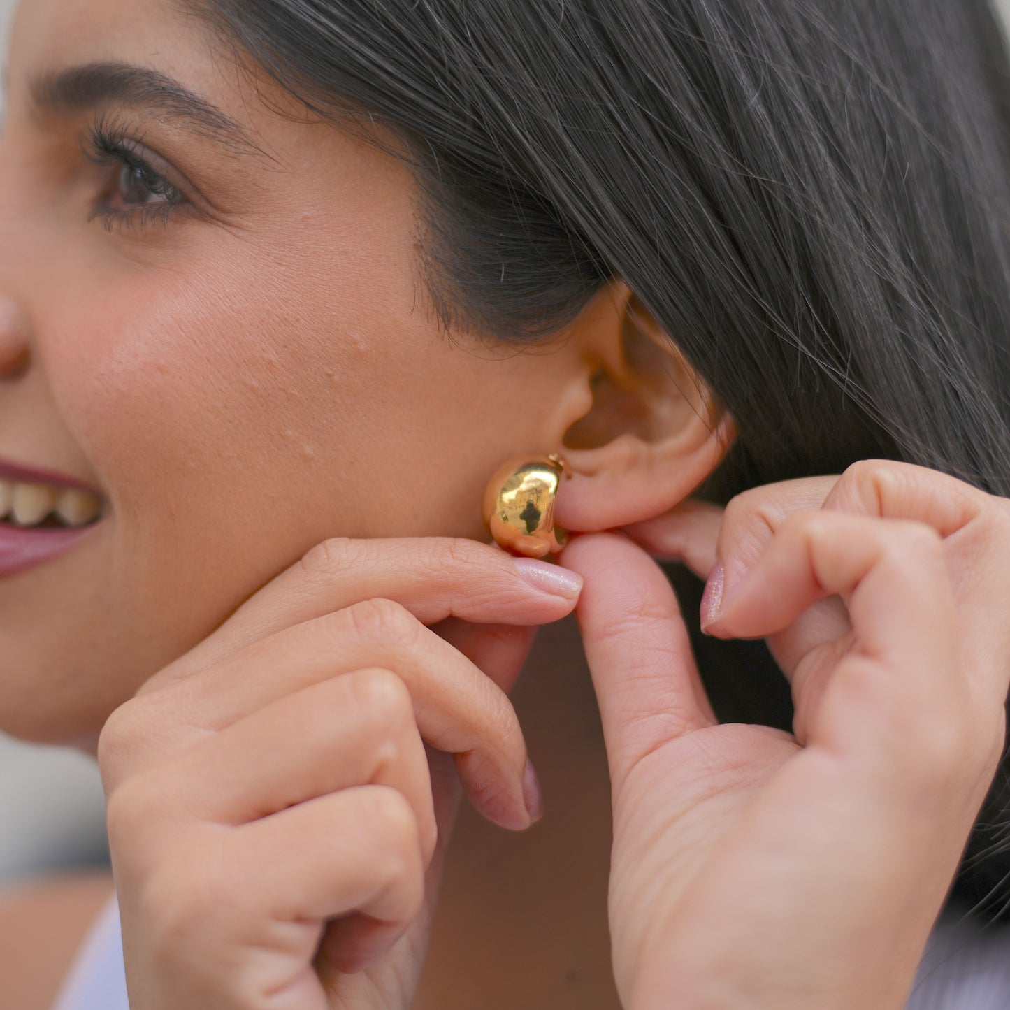 Mujer poniendose argollas de acero inoxidable doradas medianas